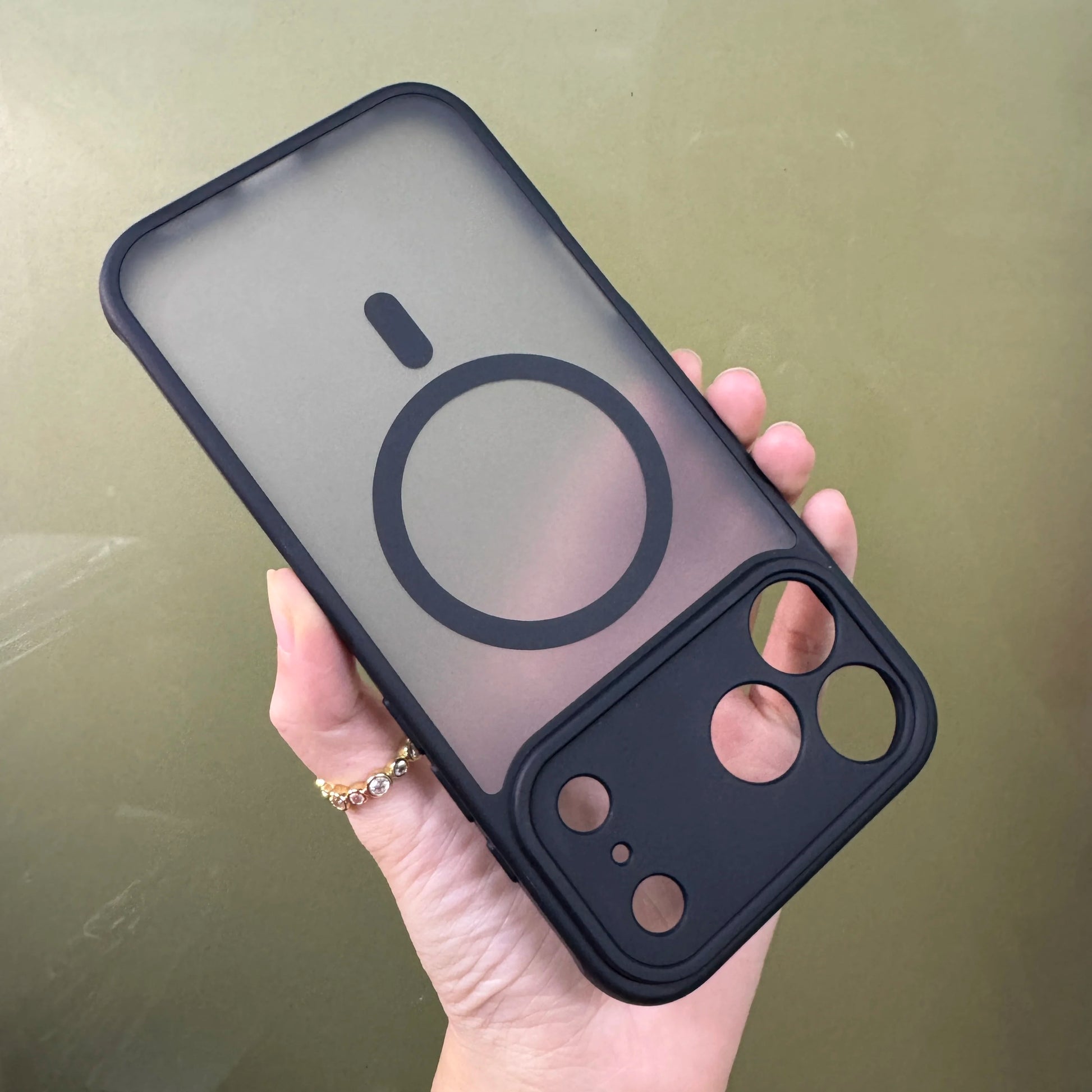 Hand holding a black Iphone 17 pro max case with Magsafe on a beige background