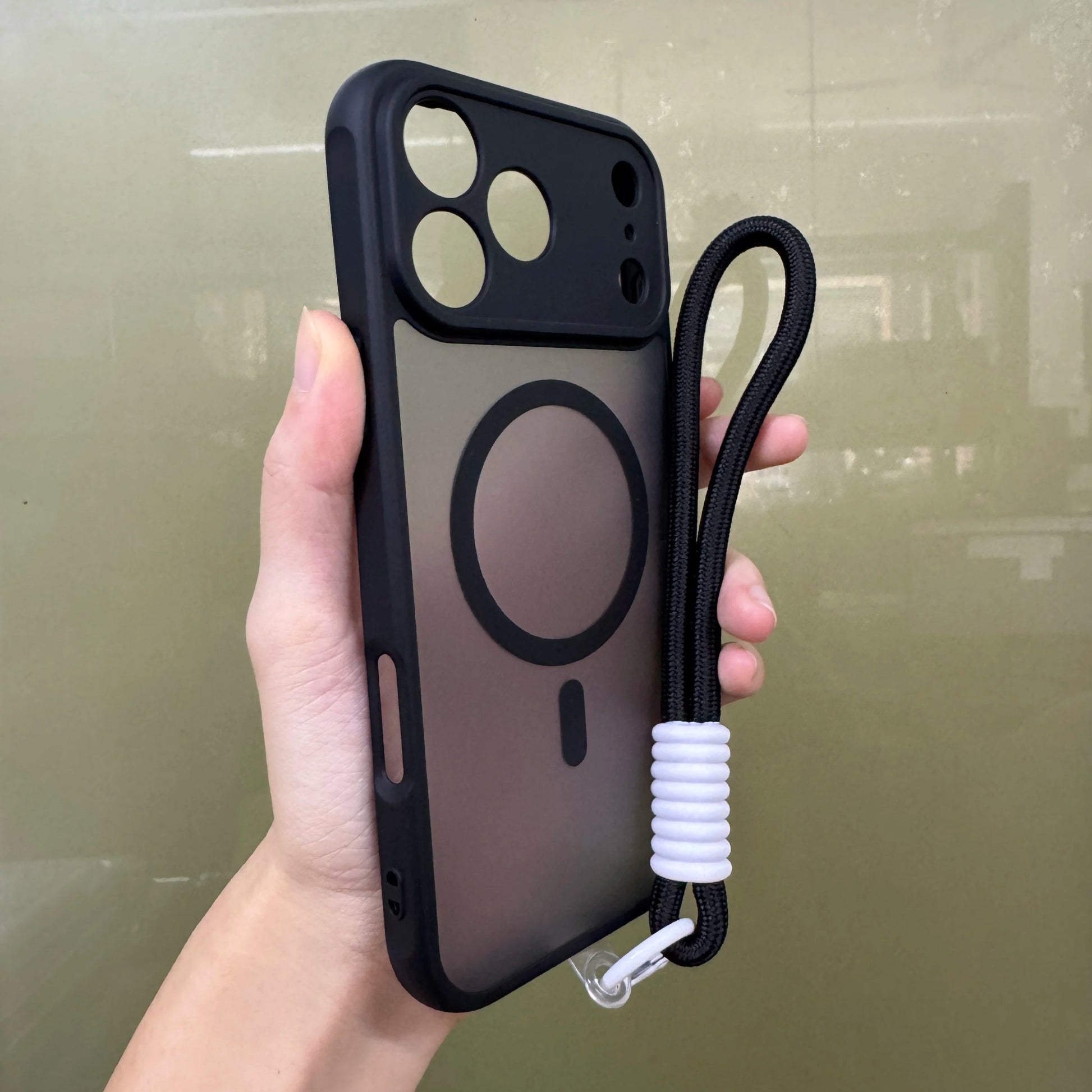 IPhone 17 Pro/pro max  case with a strap held by a hand against a plain background